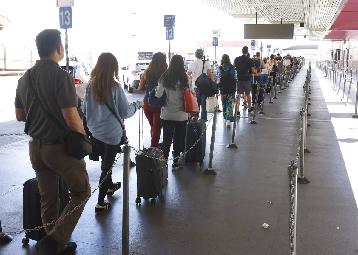 Arriving passengers at Harry Reid International Airport wait in line to take a taxi, on Friday, ...