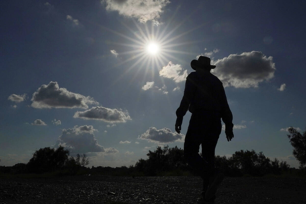 Jessie Fuentes, who works providing people with canoes and kayaks, walks along the Rio Grande w ...