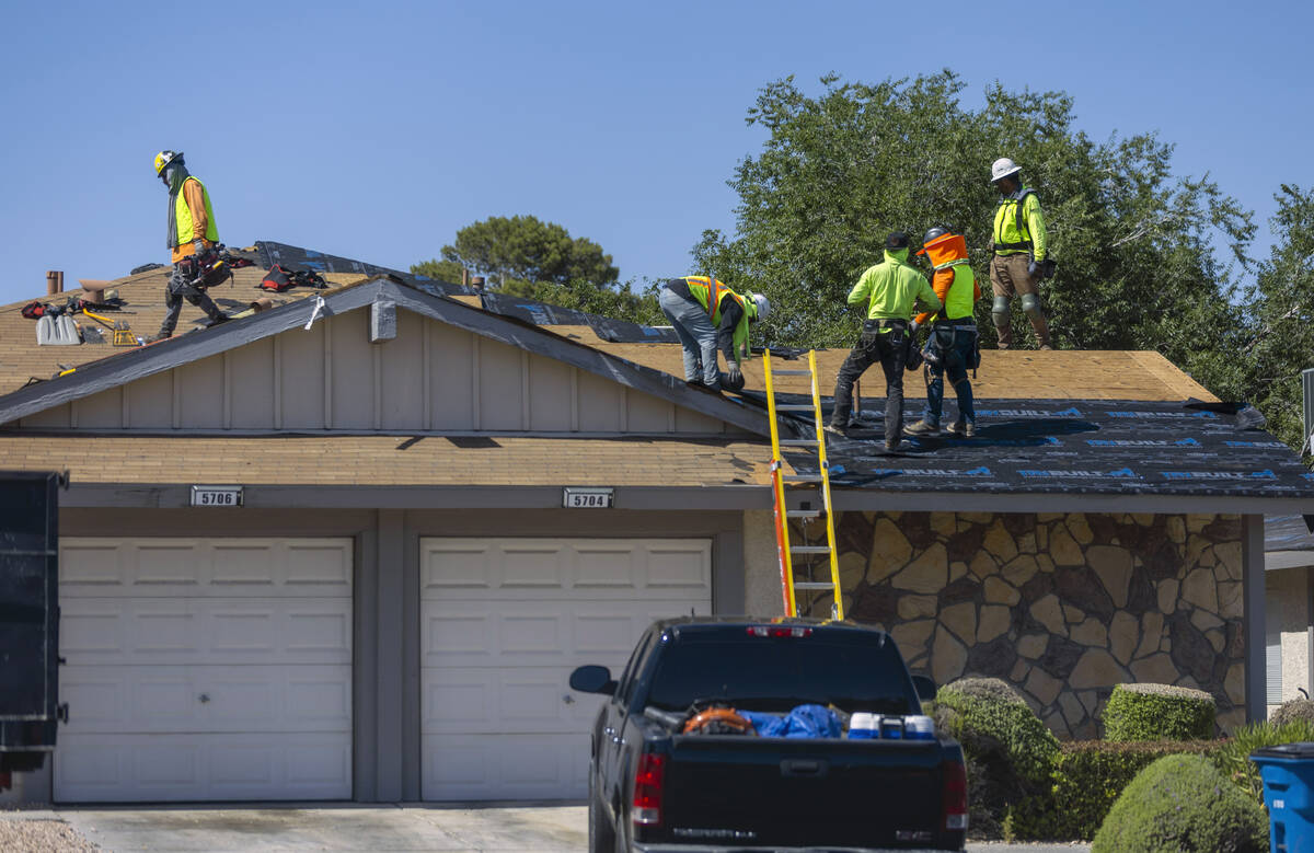 A roofing crew works atop a roof along Smoke Ranch Road as they take protections against extrem ...