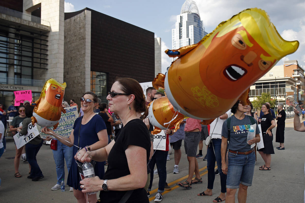 Protesters carry Trump balloons. (AP Photo/Gary Landers)