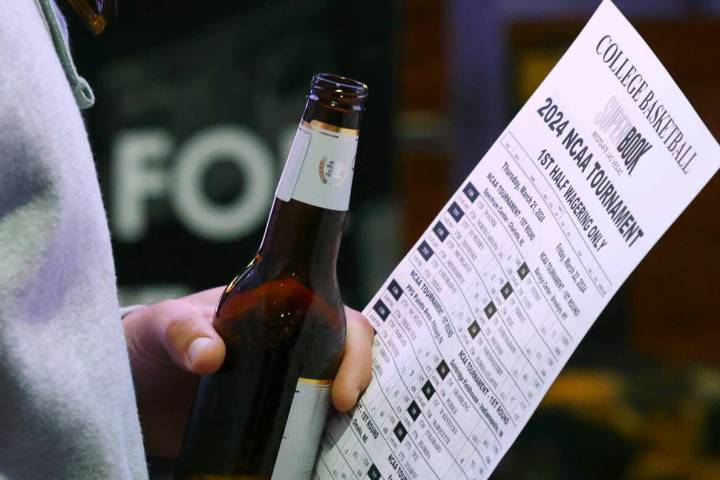 A man holds a betting sheet as he waits in line to bet on the NCAA basketball tournament at Wes ...