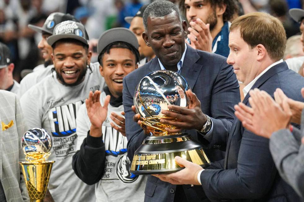 Dallas Mavericks assistant general manager Michael Finley hands the championship trophy to team ...