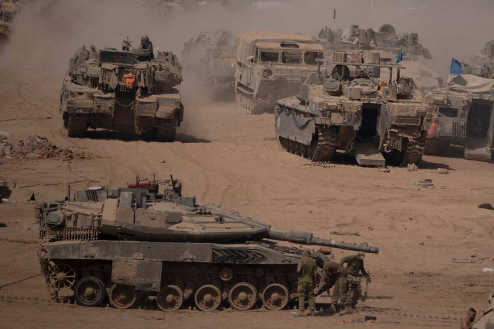 Israeli soldiers work on a tank in a staging area near the Israeli-Gaza border in southern Isra ...