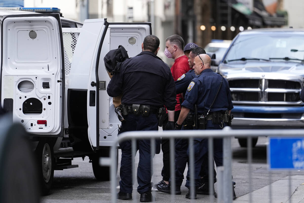 A pro-Palestinian demonstrator is escorted to a police vehicle outside a building housing the I ...