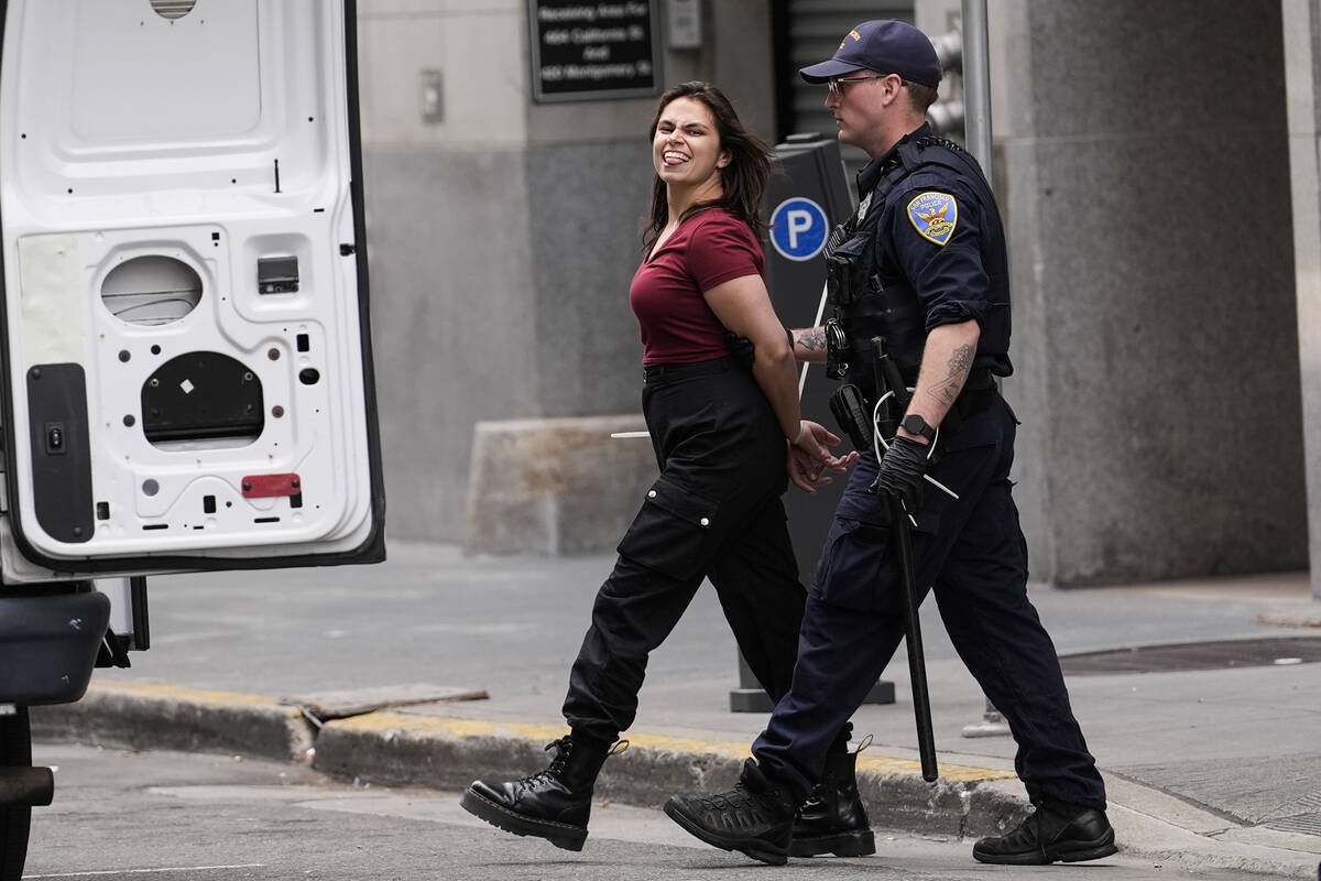 A pro-Palestinian demonstrator sticks her tongue out as she is escorted to a police vehicle out ...