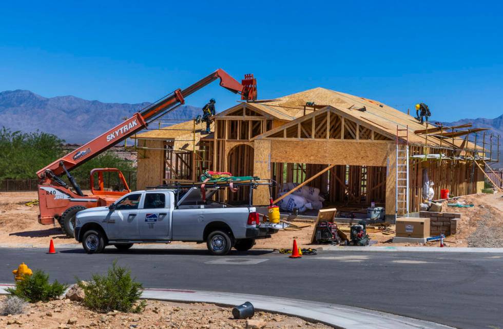 A crew works on the roof of a home within the Dusty Rose project as housing construction is at ...