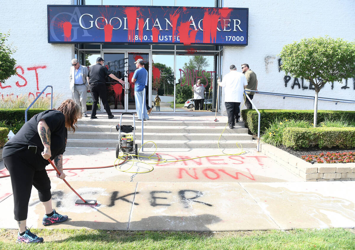 GSR Restoration project manager Tanya Holbrook scrubs spray paint on the sidewalk in front of t ...