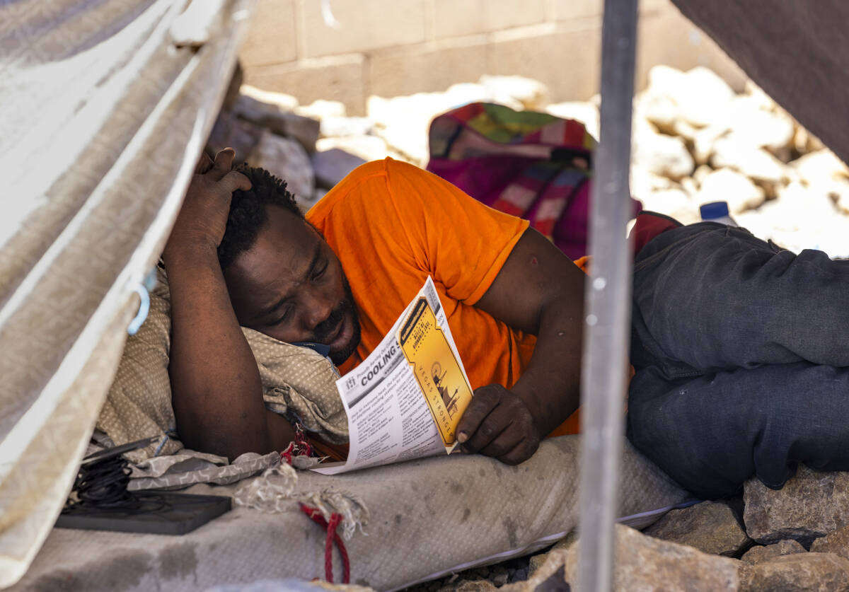 A homeless man checks out a "golden ticket" for services and a list for cooling stati ...