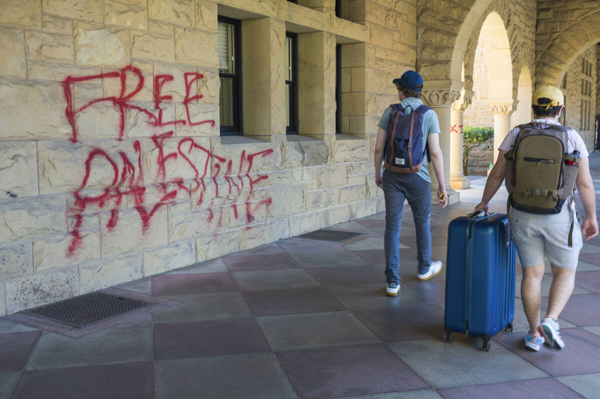 Students walk by graffiti near university president Richard Saller's office at Stanford Univers ...