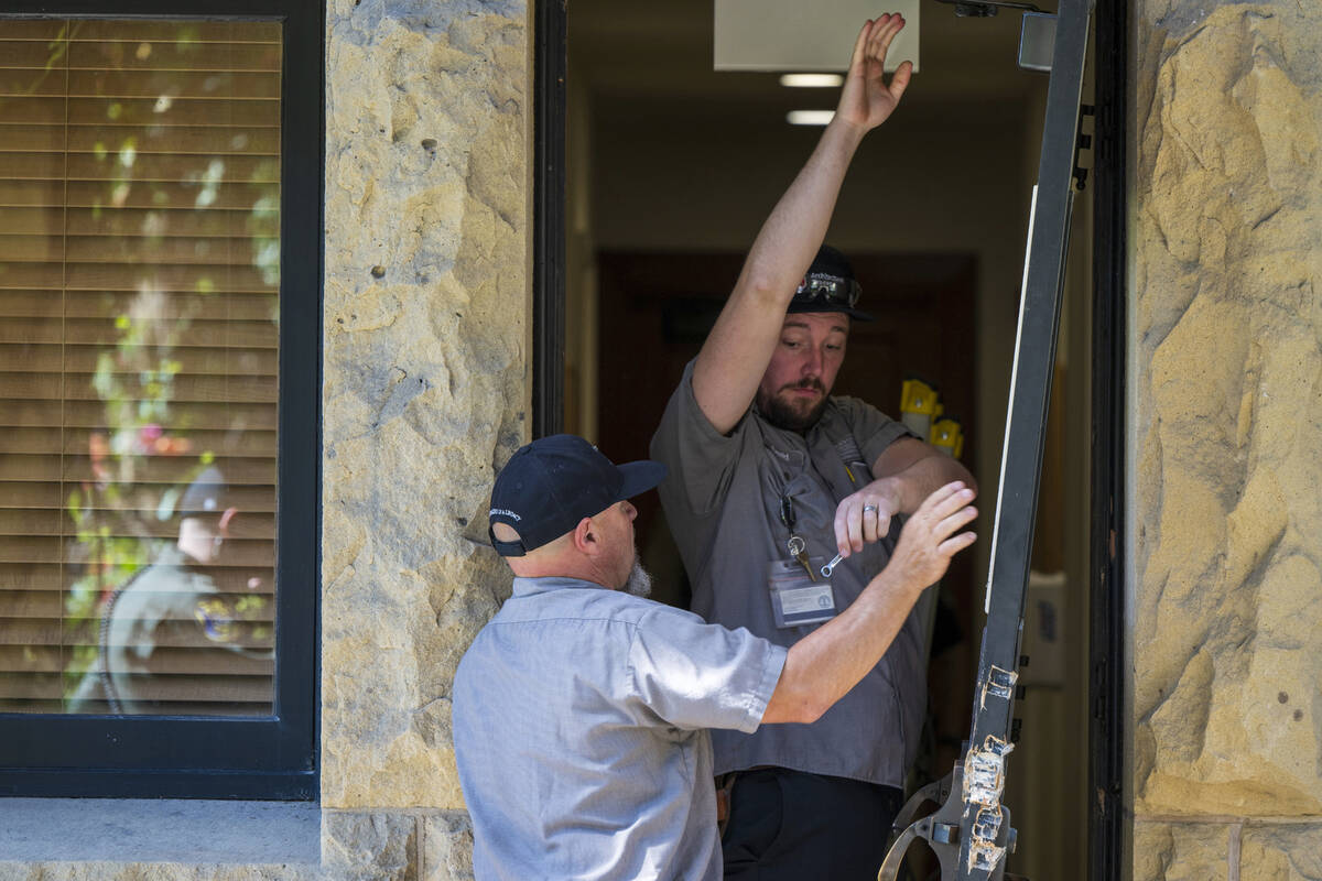 Campus maintenance workers repair a broken door at the office of the president at Stanford Univ ...