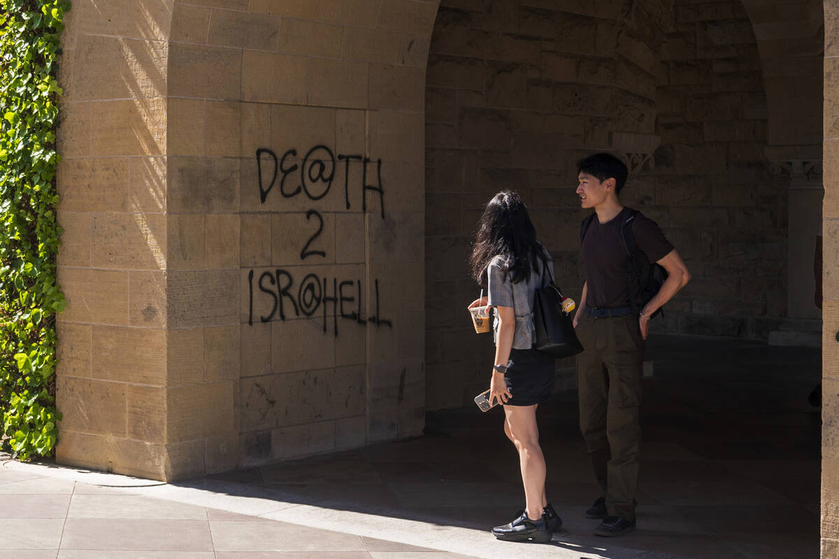 Students walk by graffiti near the office of the President at Stanford University in Palo Alto, ...