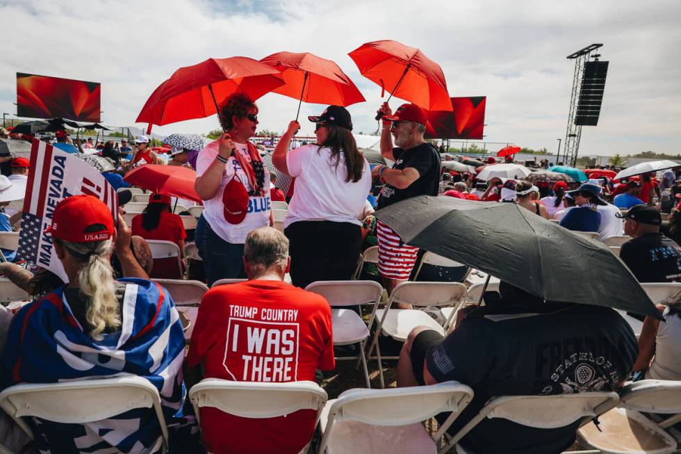 Trump supporters cool off under umbrellas at a rally for Former President Donald Trump at Sunse ...