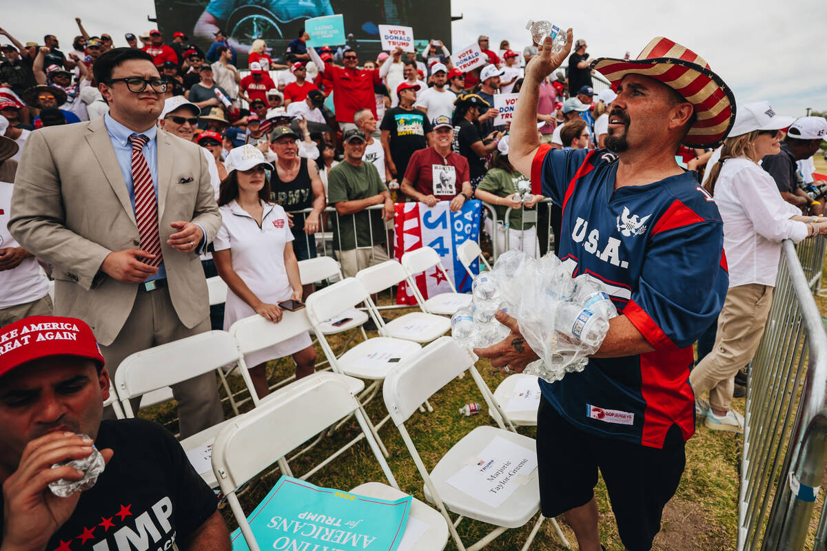 A Trump supporter throws water bottles to others during high temperatures at a rally at Sunset ...