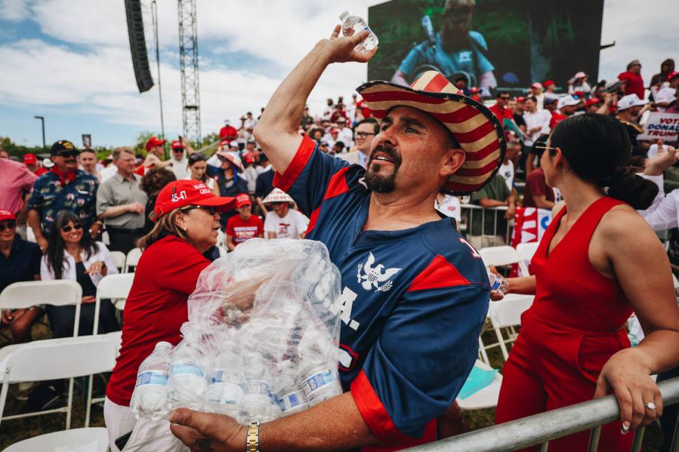 A Trump supporter throws water bottles to others during high temperatures at a rally at Sunset ...