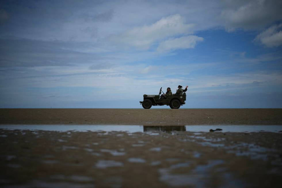 Reenactors drive a vintage US Army jeep along Utah Beach near Sainte-Marie-du-Mont, Normandy, F ...