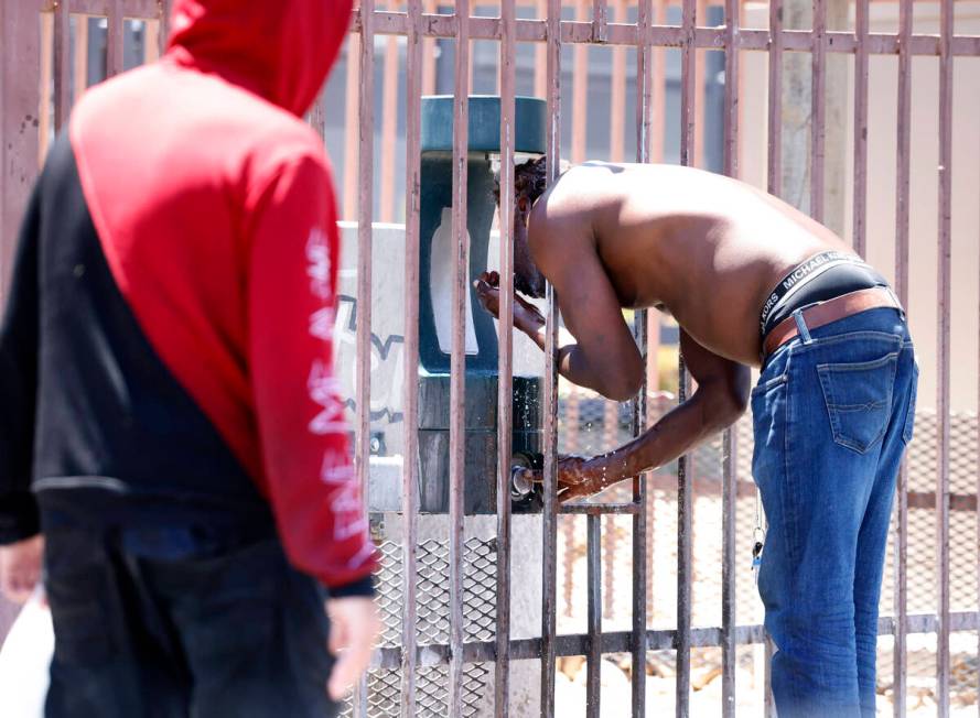 A man, who declined to give his name, cools himself at water refilling station outside of CARE ...