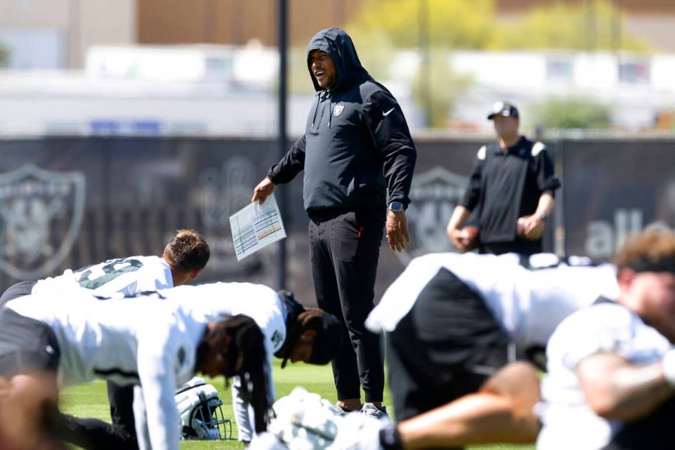 Raiders head coach Antonio Pierce watches his players stretch during team's practice at the Int ...