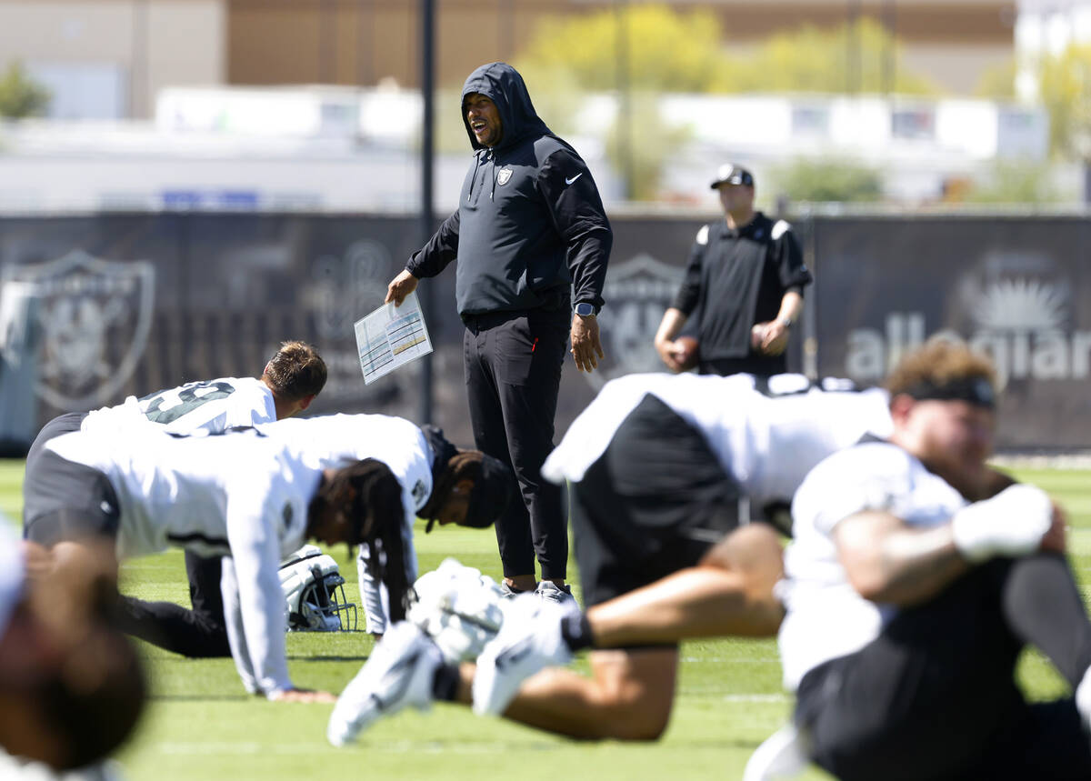 Raiders head coach Antonio Pierce watches his players stretch during team's practice at the Int ...