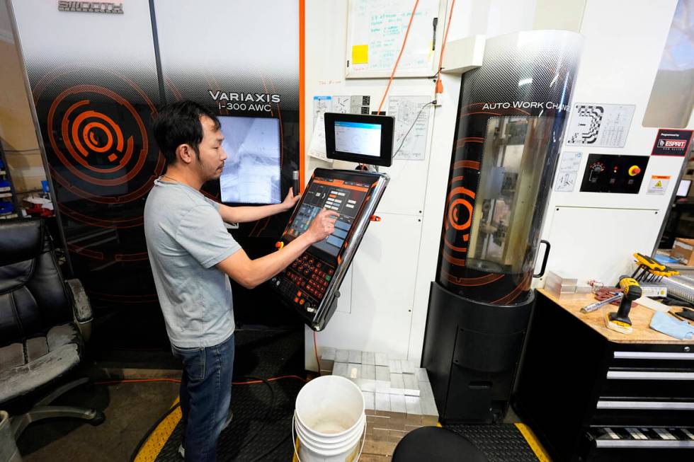 FILE - A worker at Reata Engineering and Machine Works programs a Mazak Variaxis machine used t ...