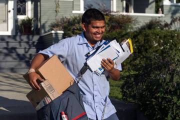 FILE - United States Postal Service letter carrier Gabriel Peña carries mail in Los Angele ...
