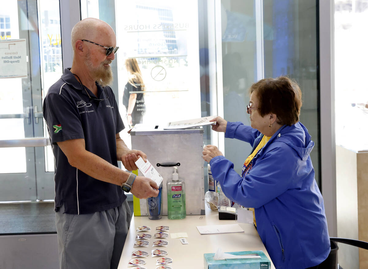 Beverly Mourachian, right, a volunteer poll worker, checks Bruce Leslie's sealed and signed bal ...