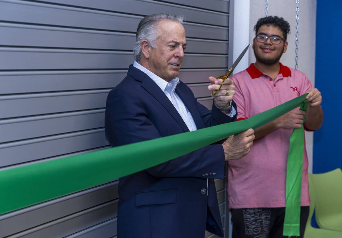 Governor Joe Lombardo readies to cut a ribbon held by student Nathaniel Solis during a visit to ...