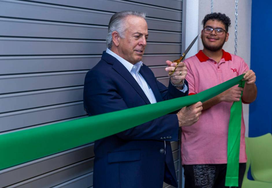 Governor Joe Lombardo readies to cut a ribbon held by student Nathaniel Solis during a visit to ...