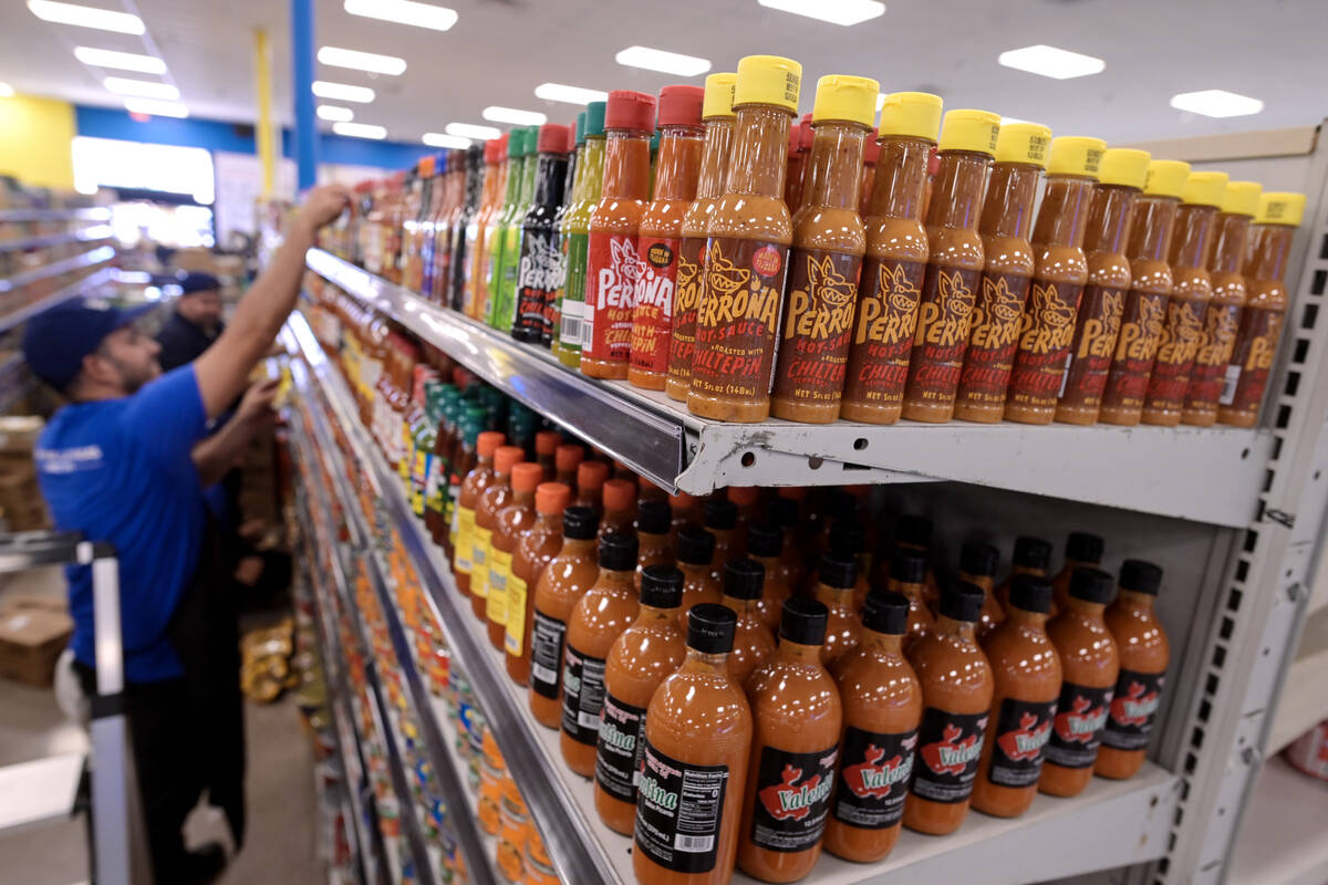 Workers stock shelves with hot sauce while preparations continue Friday, June 7, 2024, for the ...