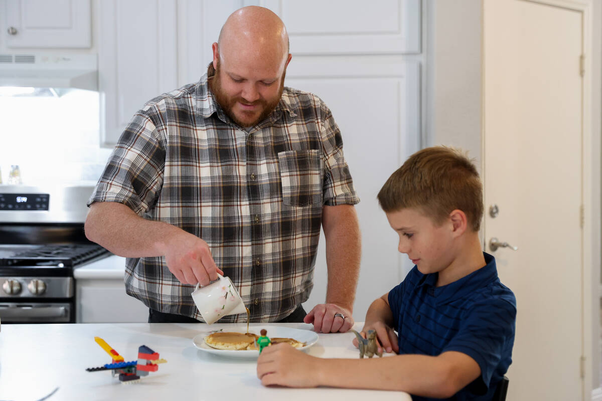 Brandon Eddy pours syrup on his son Mason’s pancakes-for-dinner at their home on Wednesd ...