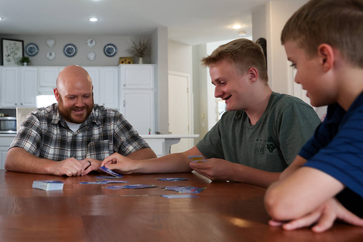 Brandon Eddy, left, and his sons Ryker, center and Mason, play a card game after dinner at thei ...