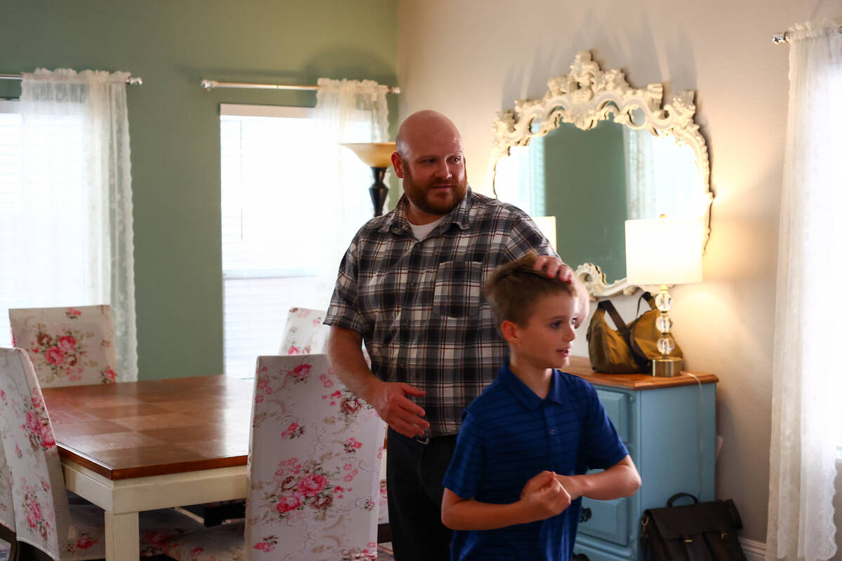 Brandon Eddy nudges his son Mason to unload the dishwasher during dinner time at their home on ...