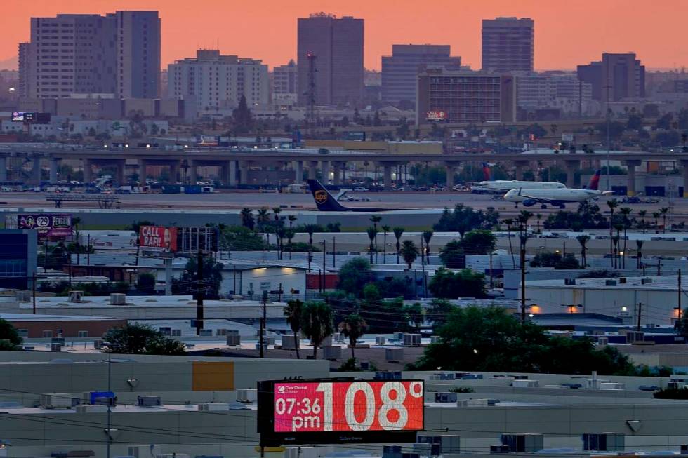 FILE - A sign displays an unofficial temperature as jets taxi at Sky Harbor International Airpo ...