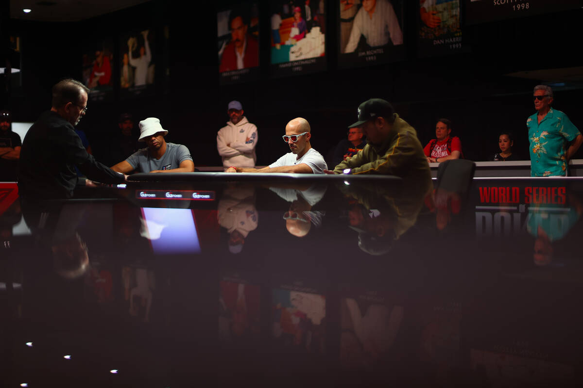Phil Ivey, left at the table, Jason Mercier, center, and Danny Wong compete during the final ta ...