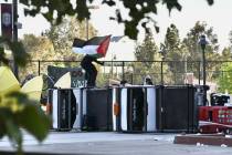 A pro-Palestinian student protester waves a Palestinian flag atop turned over utility carts whi ...