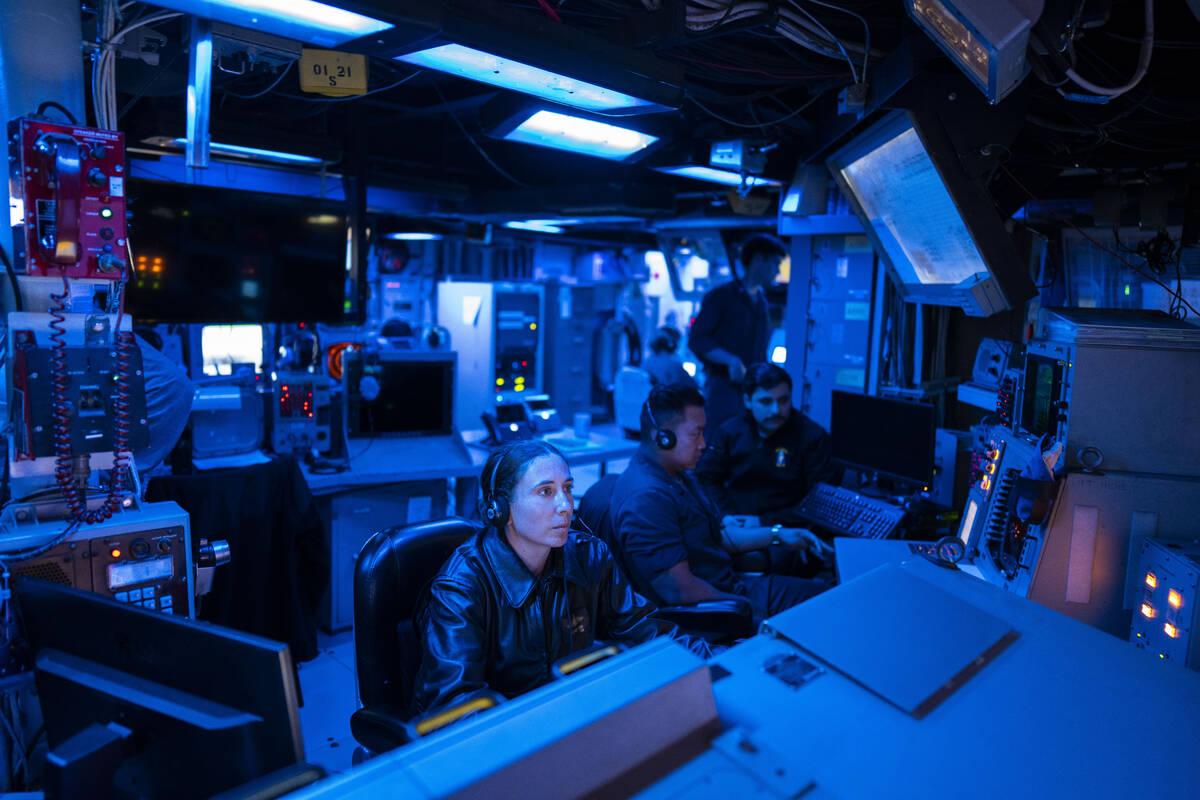 Crew members work in the combat information center of the Arleigh Burke-class guided missile de ...