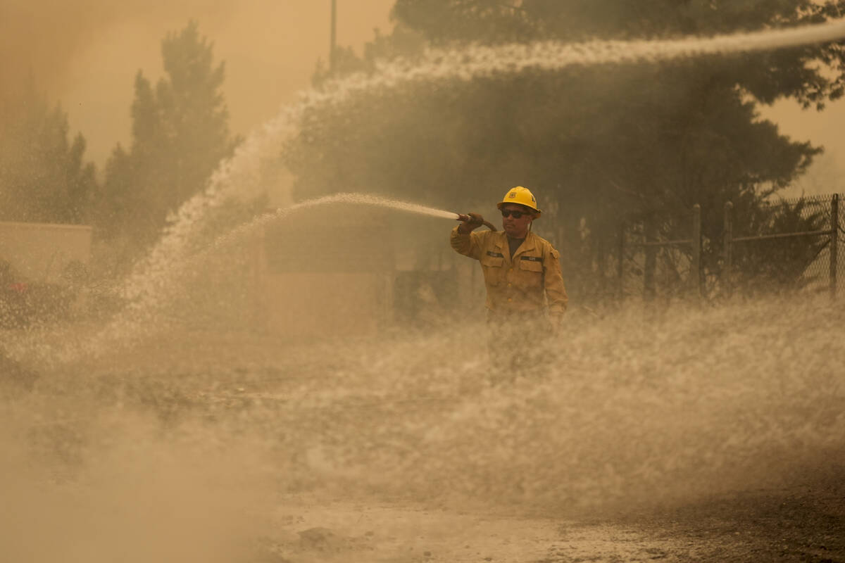 A firefighter hoses down a structure at the Los Padres Forest Station while fighting the Post F ...