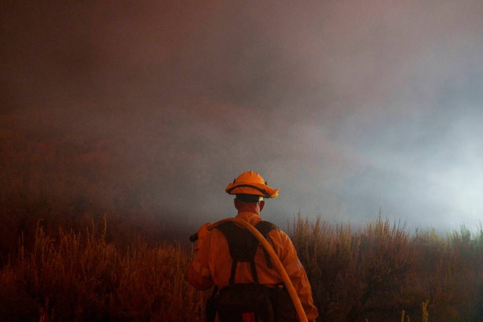 A firefighter watches for flames from the advancing Post Fire on Sunday, June 16, 2024, in Gorm ...