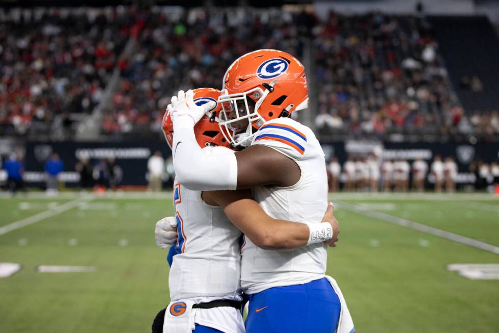 Bishop Gorman captain Elija Lofton, right, and quarterback Melvin Spicer IV embrace before the ...