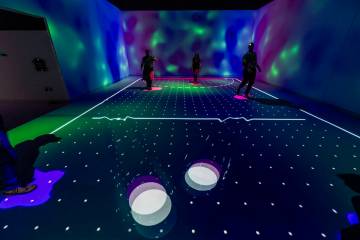 People play light hockey by kicking light projections with their feet at Electric Playhouse, a ...