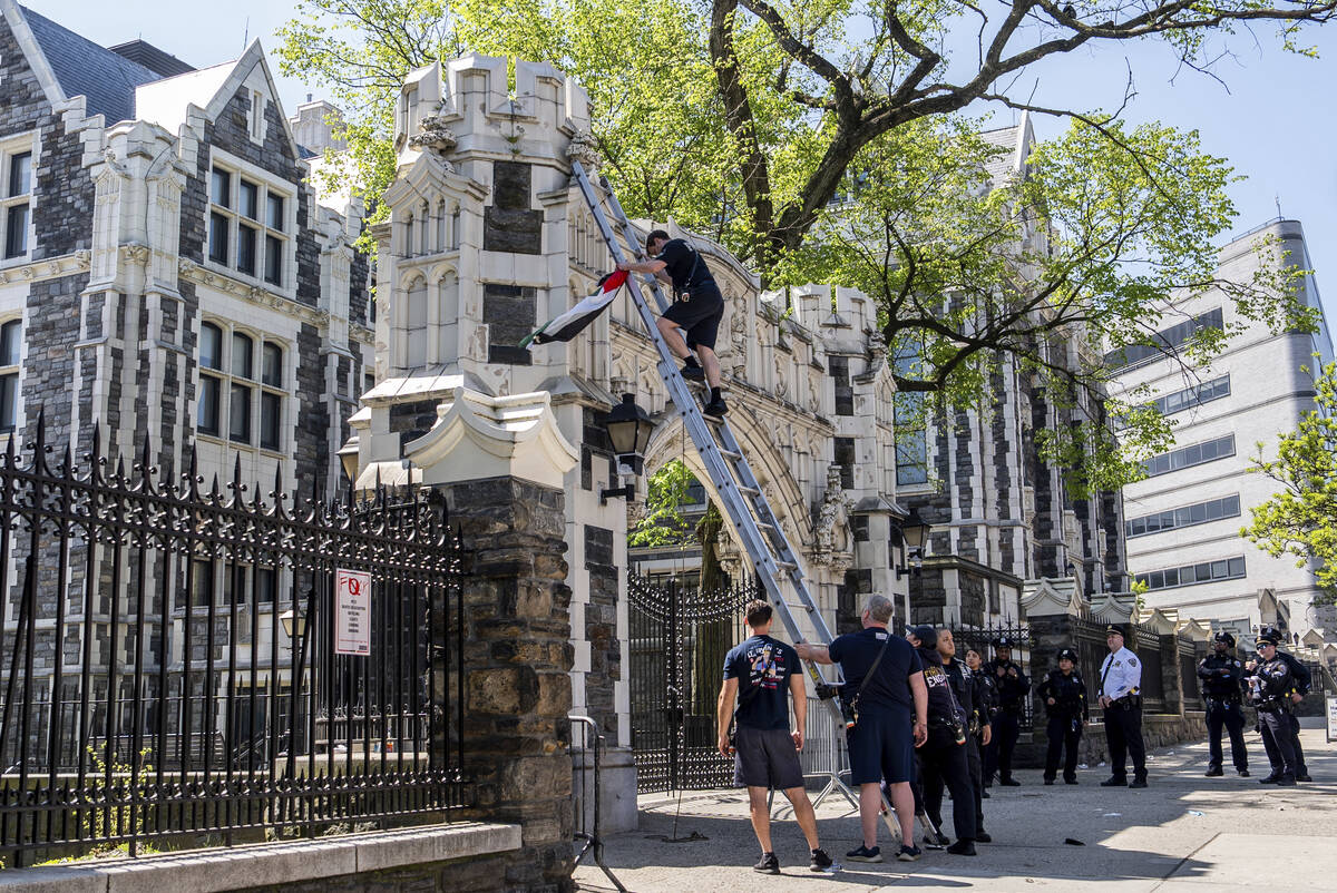 A firefighter retrieves a Palestinian flag from a gate to the City University of New York, May ...
