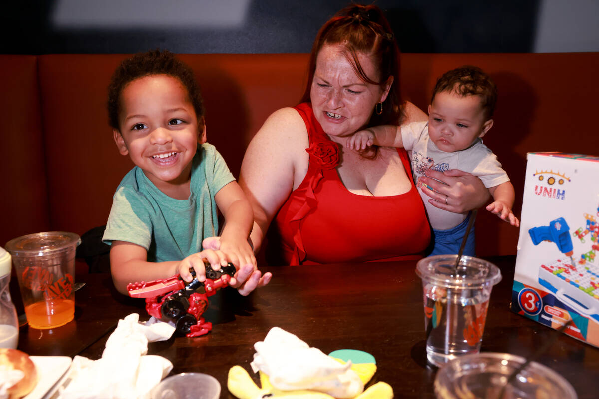 Liam Sky Walker, 2, bites his mom Melissa Walker’s finger with his new dinosaur toy as L ...