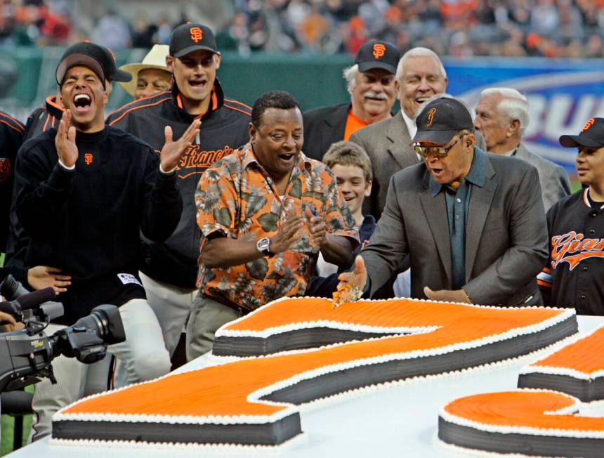 FILE - Willie Mays, right, uses his hand to chop through a large birthday cake presented in hon ...