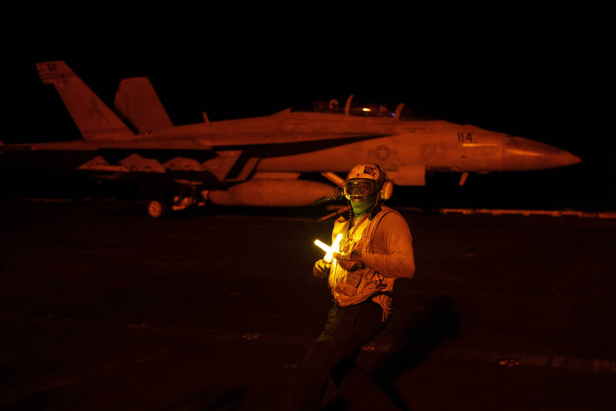 An aircraft handling officer directs a fighter jet during takeoff operations on the deck of the ...