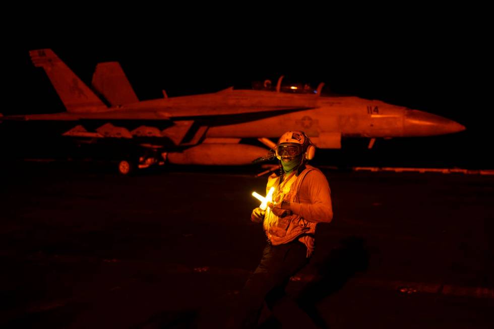 An aircraft handling officer directs a fighter jet during takeoff operations on the deck of the ...