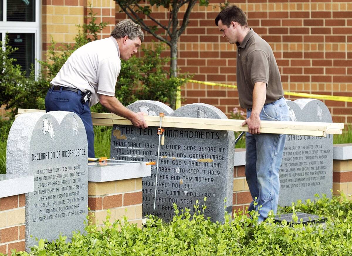 Workers remove a monument bearing the Ten Commandments outside West Union High School, Monday, ...