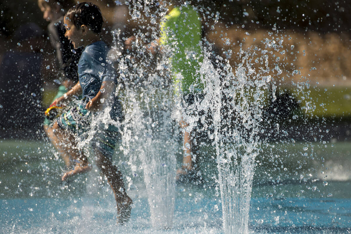 Leo Reyes, 3, runs through the water fountains as he stays cool on the splash pad at The Paseos ...