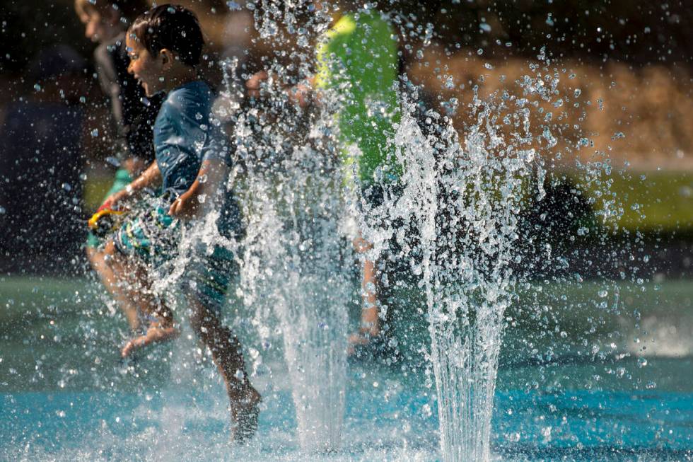 Leo Reyes, 3, runs through the water fountains as he stays cool on the splash pad at The Paseos ...