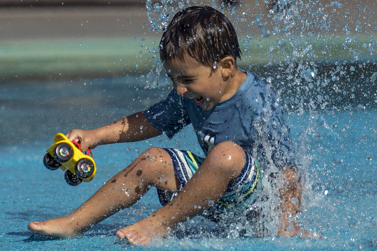 Leo Reyes, 3, sits on a water fountain as he stays cool on the splash pad at The Paseos Park on ...