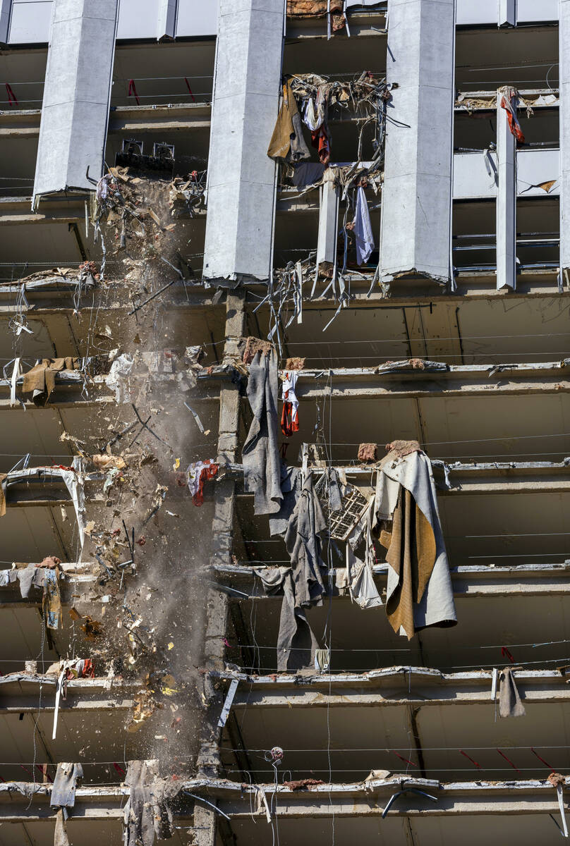 Debris is pushed out of a higher floor to a pile below for transport as demolition continues on ...