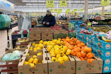 A man looks at his mobile phone while shopping at a grocery store in Buffalo Grove, Ill., Sunda ...